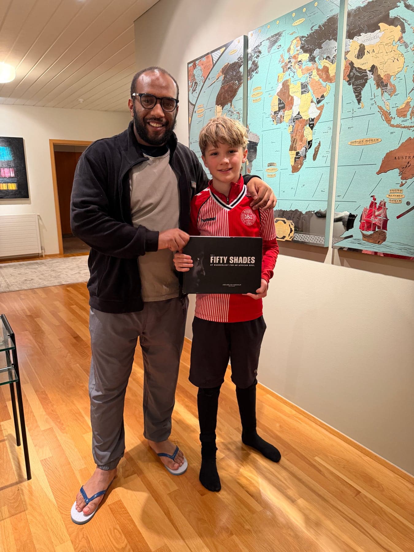 Abduselam Ademnur sharing his book with a young reader in front of a world map