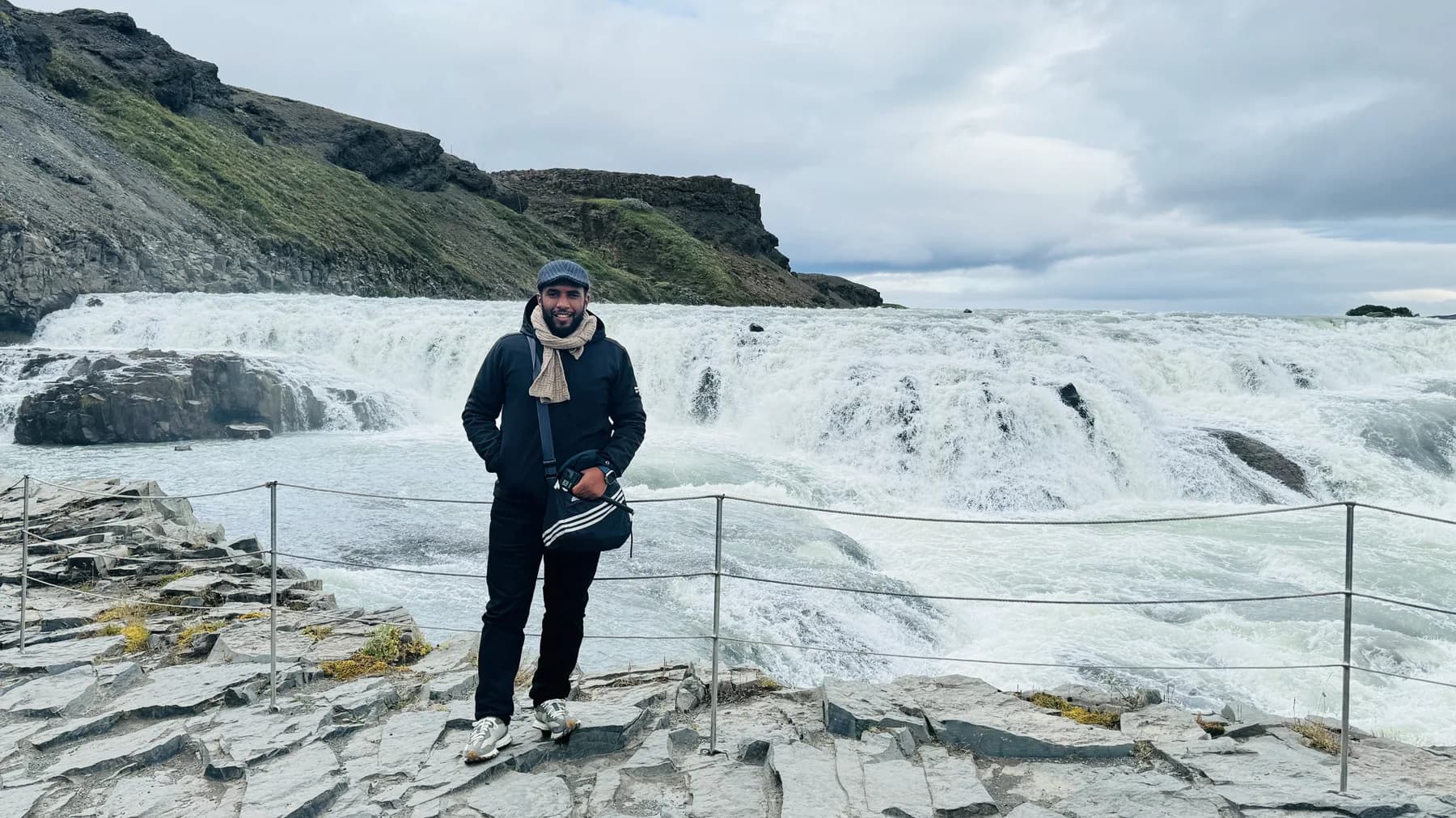 Abduselam standing before a broad glacial waterfall in Iceland