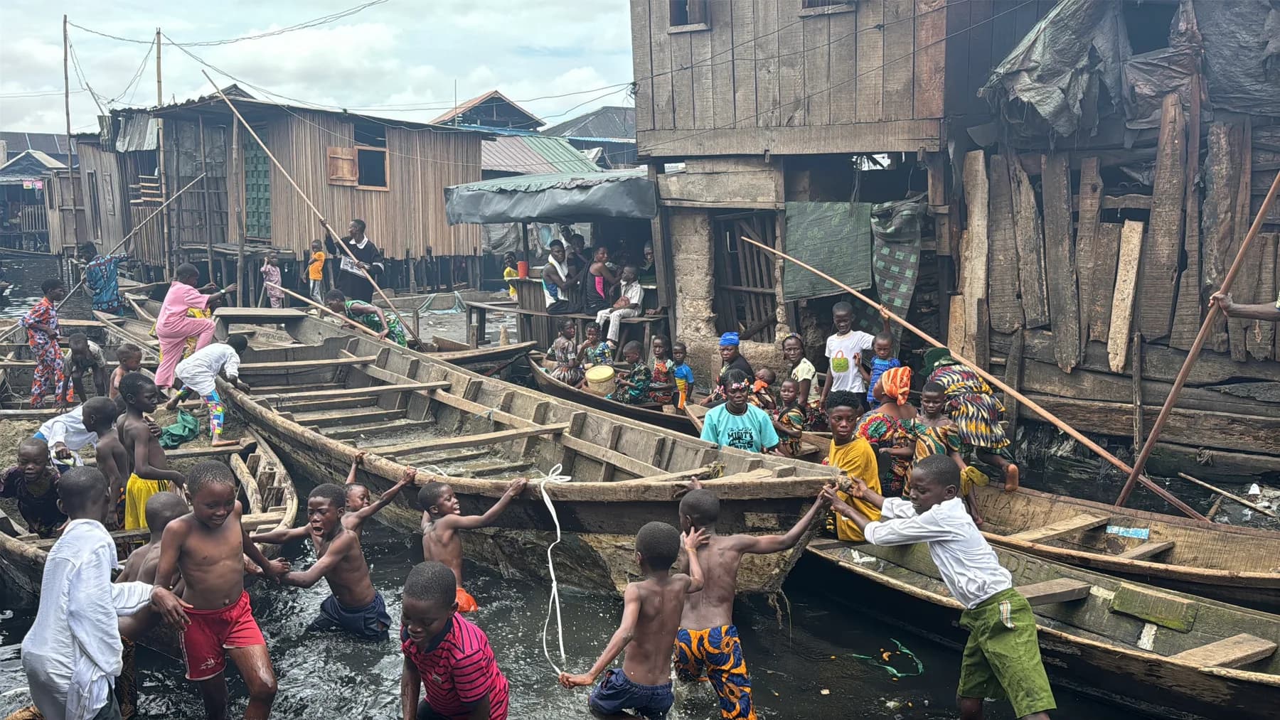Children and families among wooden boats in a waterfront neighborhood in Nigeria